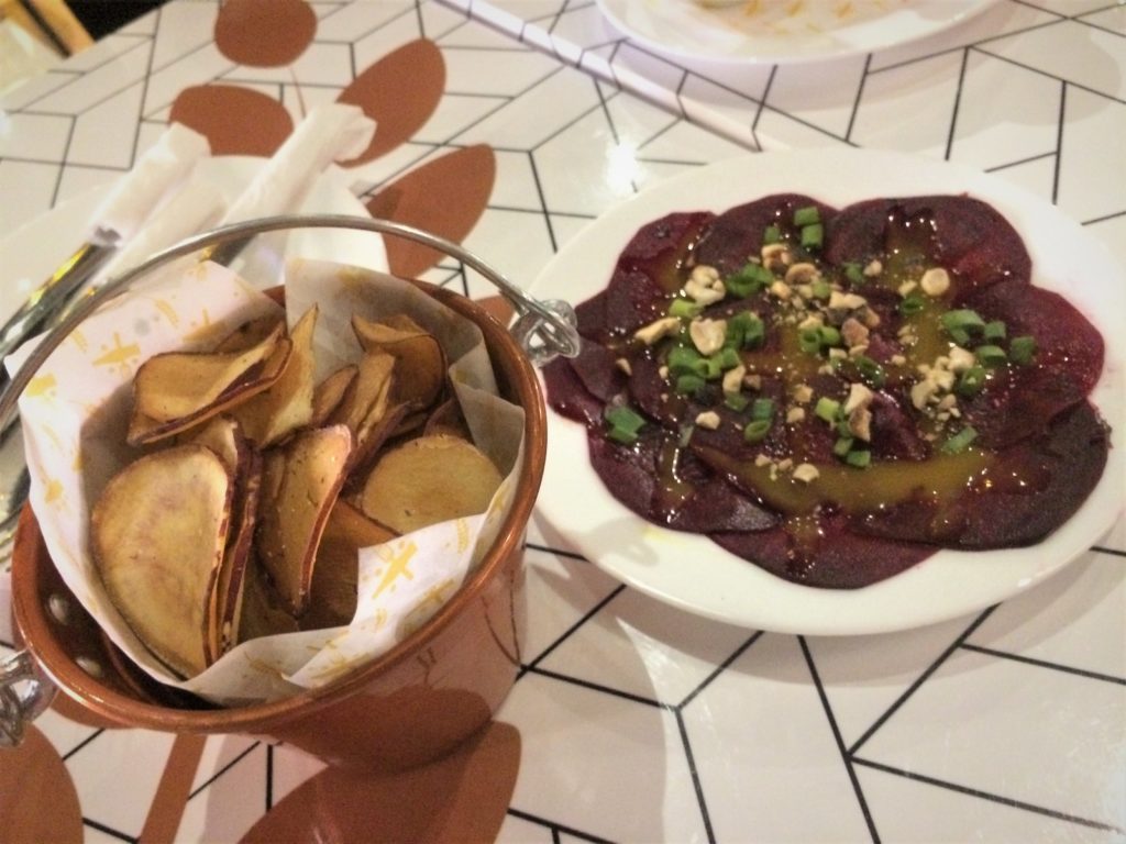 carpaccio de beterraba marinada, com molho de mostarda e mel, finalizadas com ervas frescas, raspas de limão siciliano e castanha, acompanhado de chips de batata doce