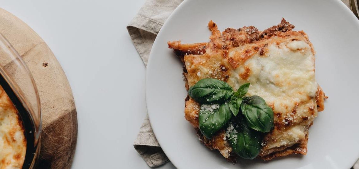 Prato de lasanha com generosas camadas de molho branco, massa e recheio, proporcionando uma experiência gastronômica irresistível e reconfortante.