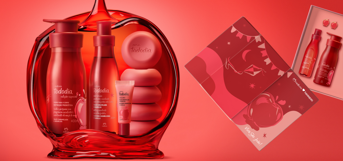 Imagem da linha Natura Tododia Maçã Caramelada e Baunilha com hidratante corporal 400ml, body splash 200ml, gloss labial, sabonetes em barra e caixa do kit exclusivo da collab com Havaianas, contendo chinelo vermelho e pin em formato de maçã do amor. Embalagens em tons vermelhos e dourados, inspiradas na maçã do amor, fragrância gourmand doce com notas de maçã vermelha, baunilha e caramelo. Cosméticos veganos para autocuidado e beleza com aroma de sobremesa, lançados para o período junino.