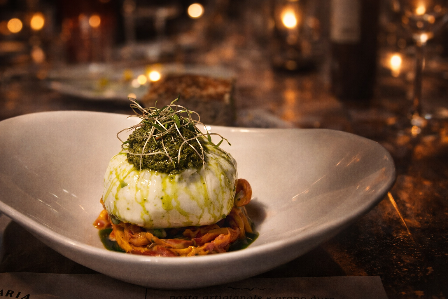 Burrata al pesto Burrata de bufala servida com mix de tomates vermelhos. e amarelos em três texturoL pesto de manjericão e focaccia 